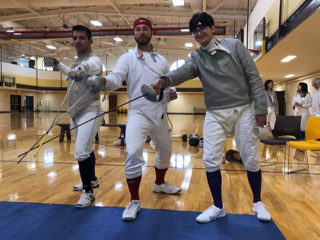 four winning fencers from tournament holding sabers downward with tip of blades together